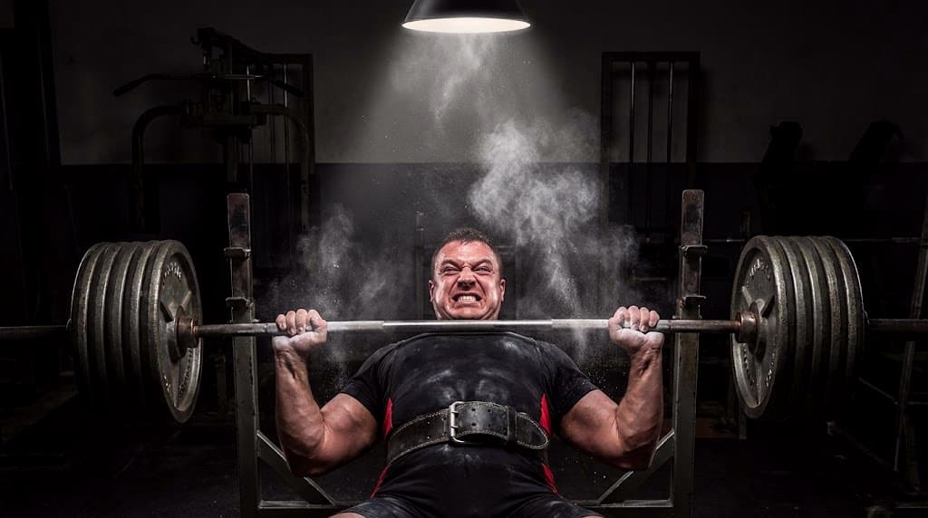 Homme concentré sous une barre de développé couché chargée